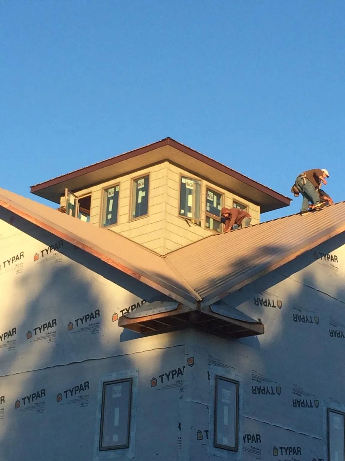 Roofers working around a rooftop cupola on a new metal roof at sunset — Roof Waterproofing in Tipton by Roofing Brothers